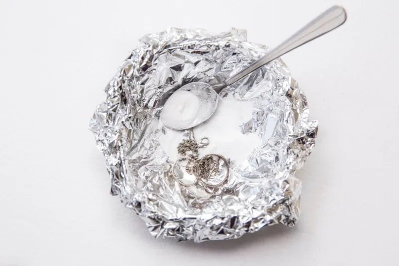 A Solution Of Baking Soda(sodium Bicarbonate) And Warm Water Will Remove The Tarnish From Silver When The Silver Is In Contact With A Piece Of Aluminium Tin Foil. Pouring Hot Water Over Silver.
